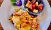 Lobster & Sausage Hash Benedict with zesty Hollandaise served with fresh lime dressed fruit bowl.